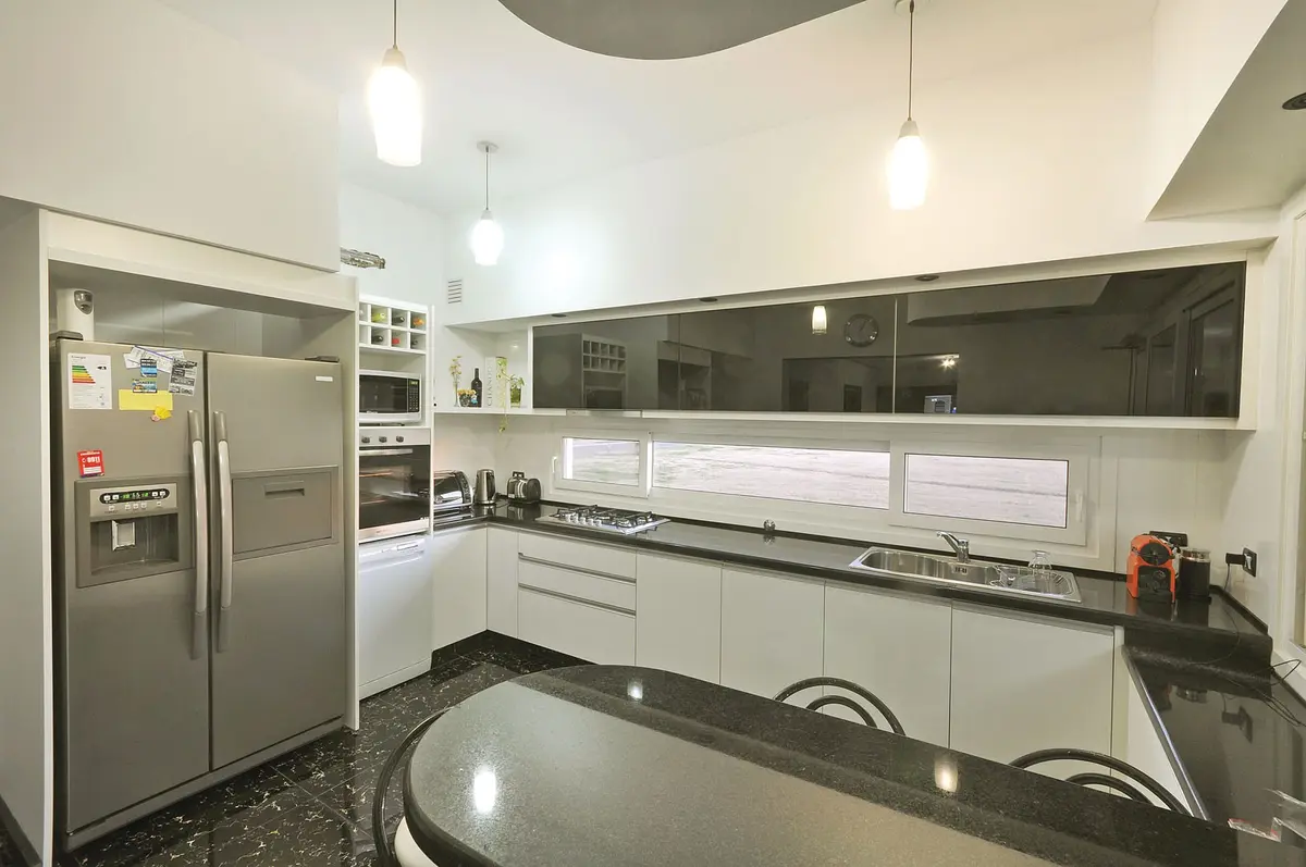 Cozinha moderna linear branca com bancada de pedra preta e ilha — projeto Casa 4, por Fhee Construcciones, em Nordelta