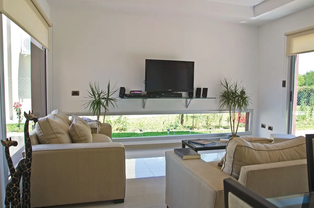 Sala de estar moderna com janelas grandes e sofá bege — projeto Casa 2, por Fhee Construcciones, em Rincón de La Costa
