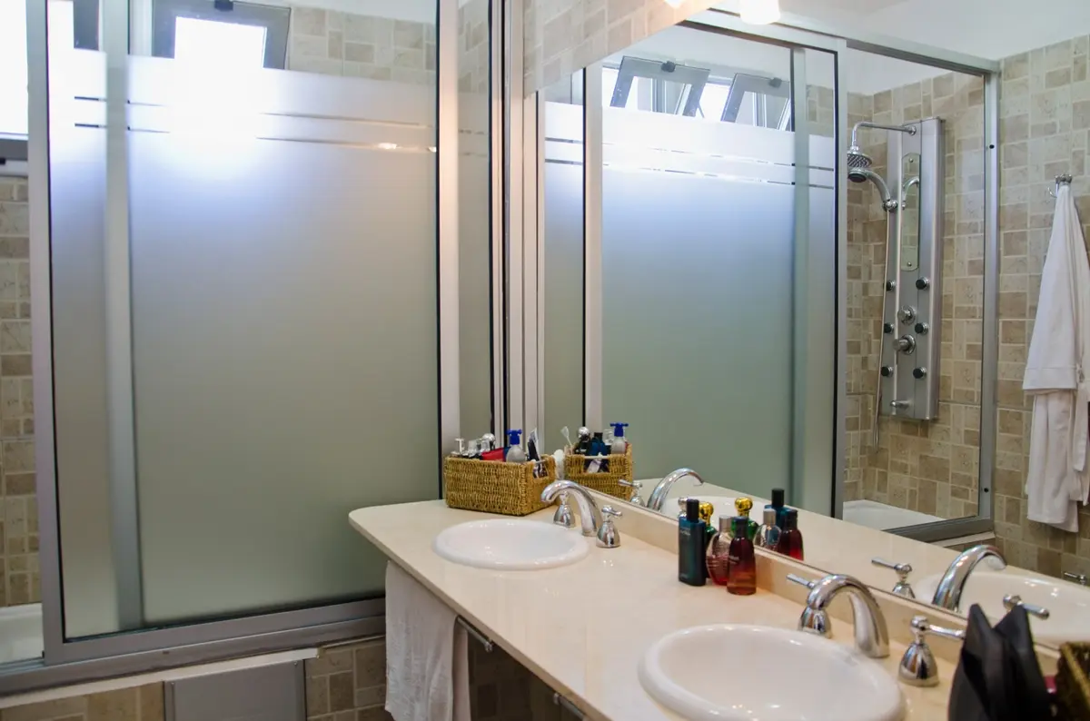 Baño moderno con doble lavabo, encimera de mármol y grandes ventanales — proyecto Casa 2, por Fhee Construcciones, en Rincón de La Costa
