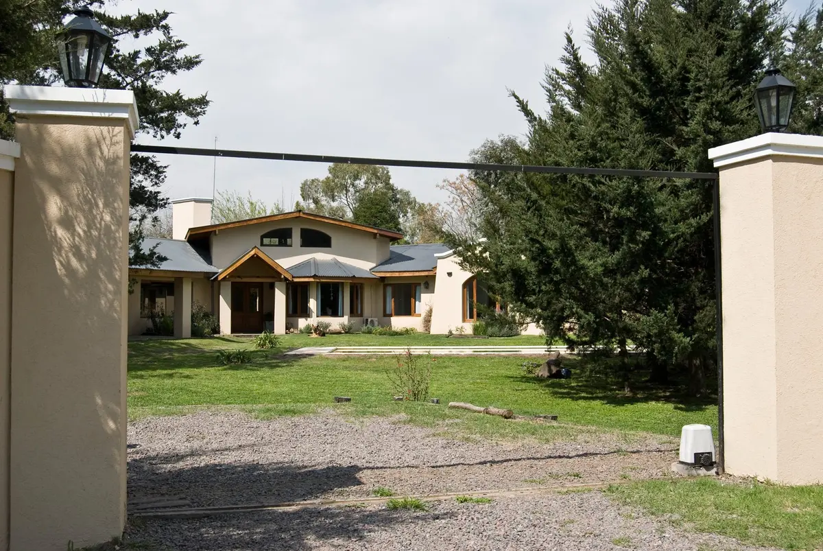 Fachada de casa de campo con portón de rejas — proyecto Casa 1, por Fhee Construcciones, en El Cazador