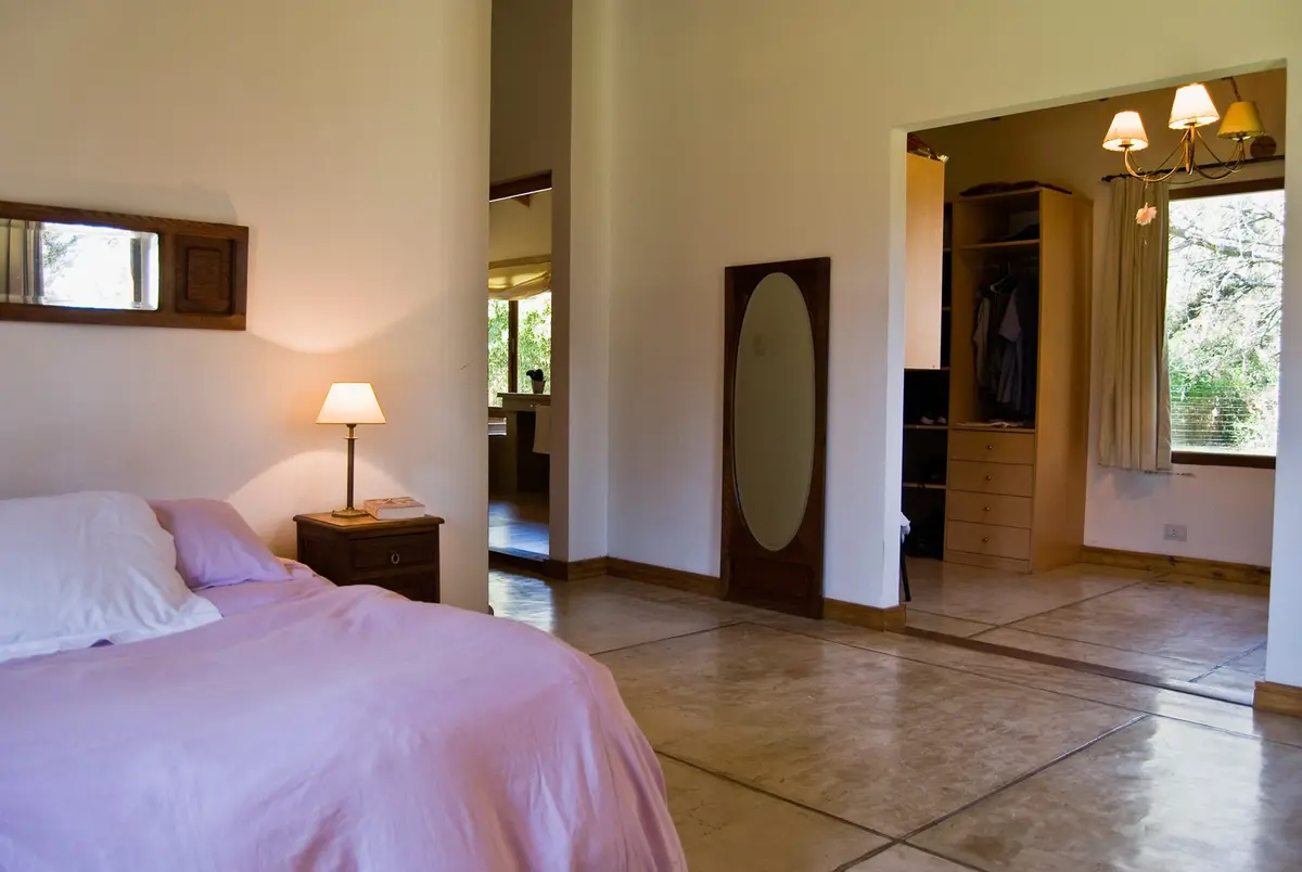 Dormitorio con piso de cemento pulido y vista al exterior — proyecto Casa 1, por Fhee Construcciones, en El Cazador
