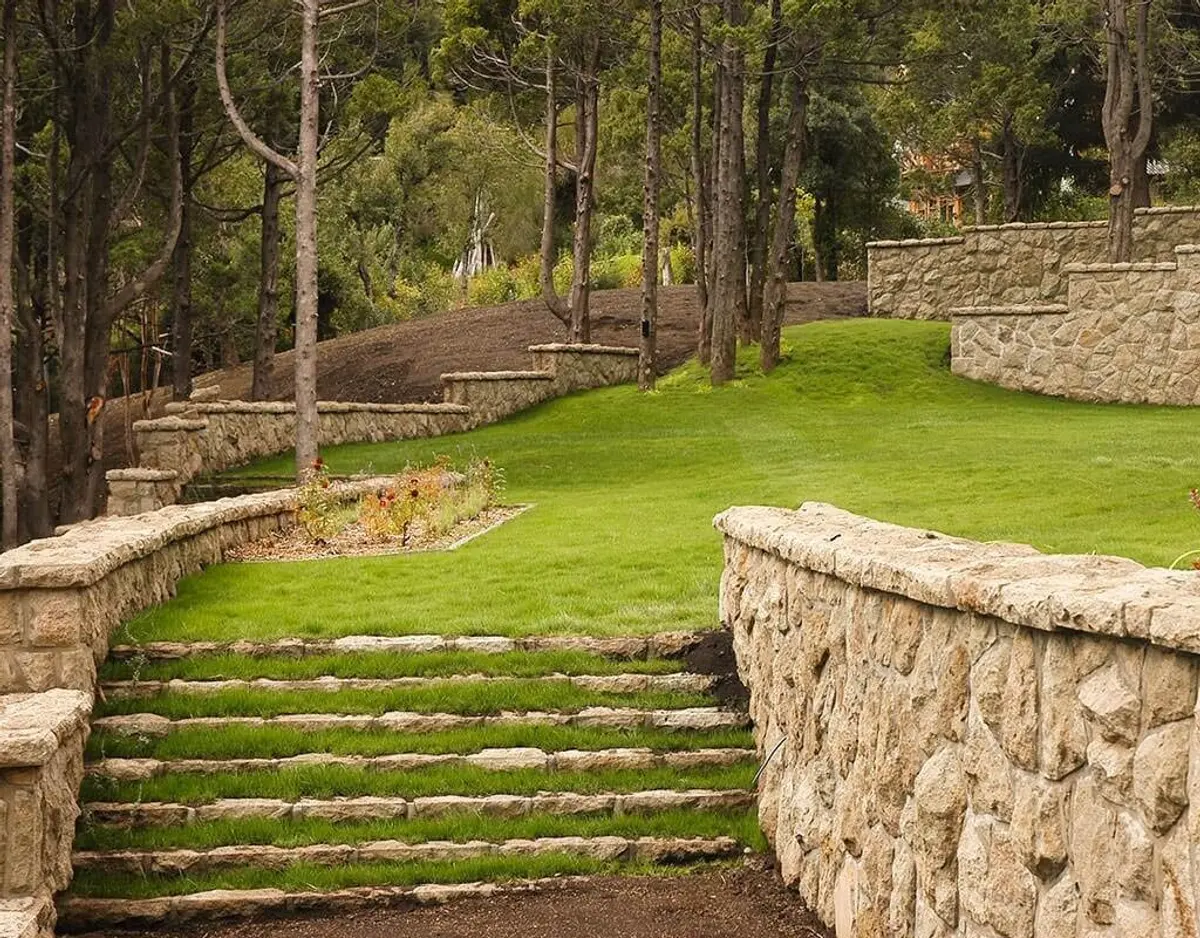 Jardim com degraus e muros de pedra em floresta — projeto Corrientes del Nahuel, por Ricardo Pereyra Iraola, em Bariloche