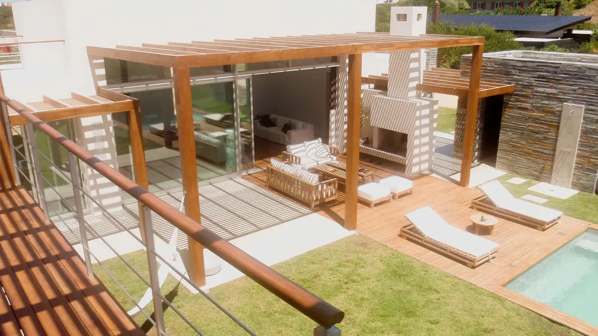 Área de lazer moderna com deck de madeira, piscina e área de estar externa — projeto Costa Uruguaya, por Ricardo Pereyra Iraola
