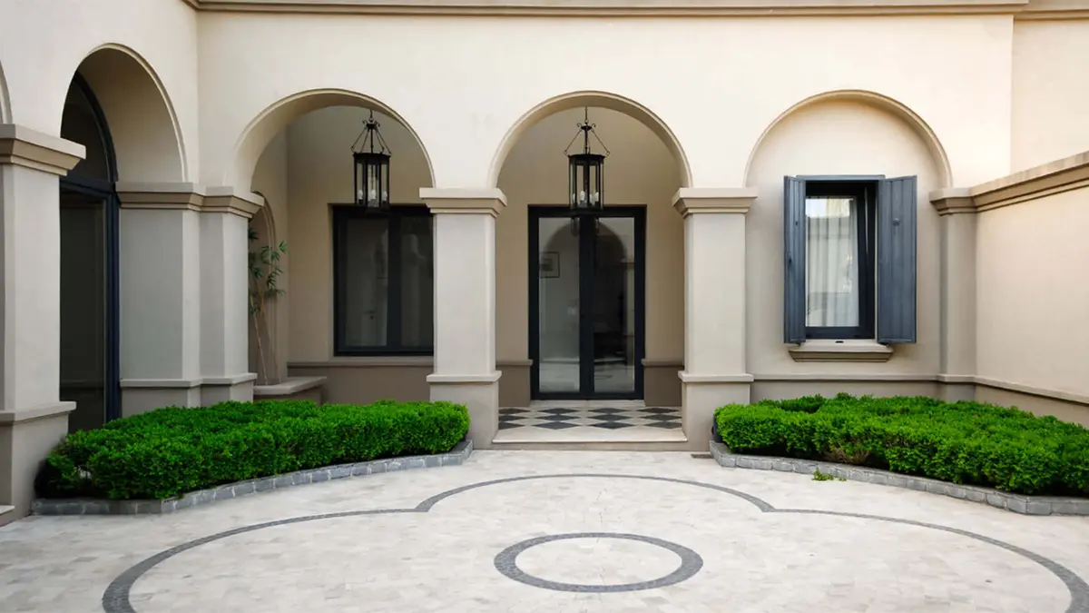 Fachada residencial mediterrânea com arcos e jardim exuberante — projeto Elegante Equilibrio, por Ricardo Pereyra Iraola