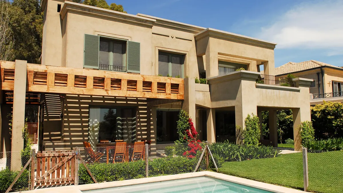 Fachada de moderna vila mediterrânea com pergolado e piscina — projeto Fondo al Golf, por Ricardo Pereyra Iraola