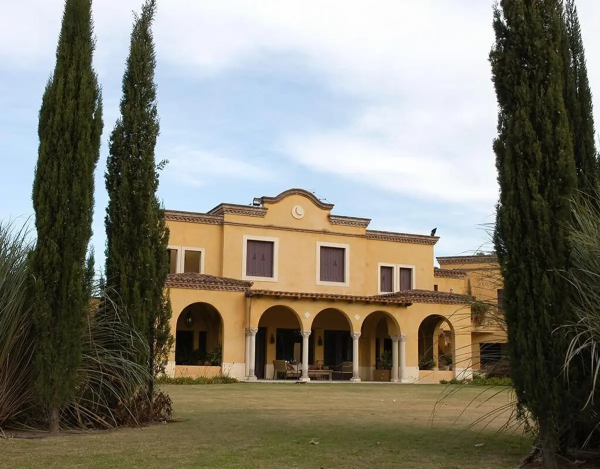 Fachada estilo mediterráneo con árboles cipreses y jardín — proyecto Gitana, por Ricardo Pereyra Iraola 