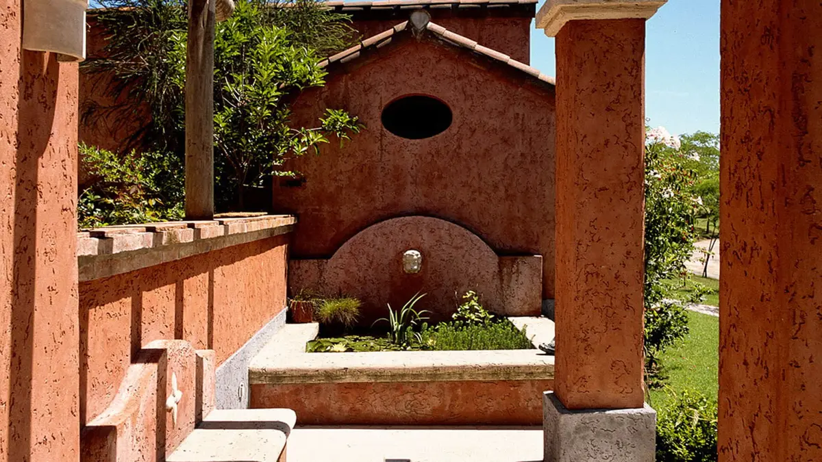 fachada mediterrânea com arcos e fonte de pedra — projeto Las Arcadas, por Ricardo Pereyra Iraola