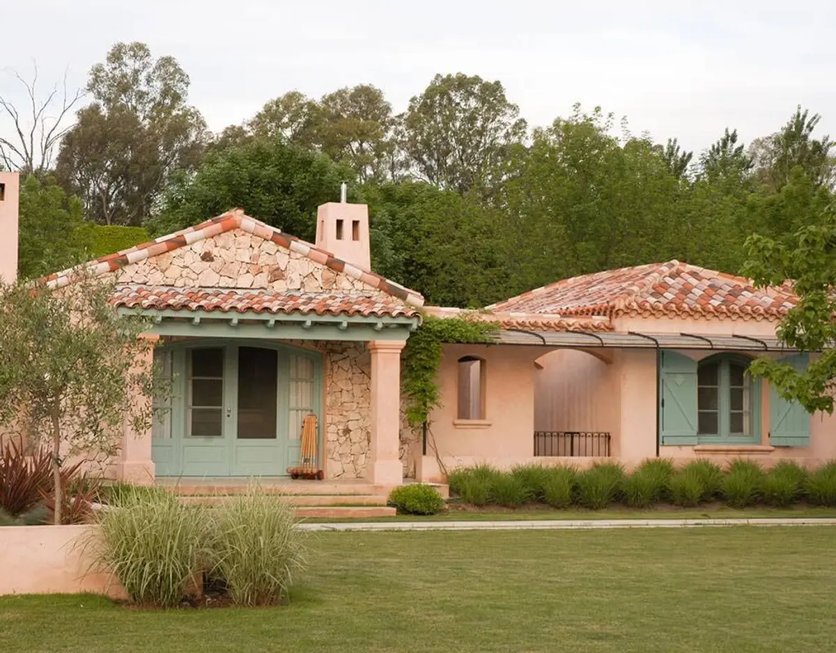 Fachada de estilo mediterráneo con techo de tejas y patio con muebles — proyecto Les Confines, por Ricardo Pereyra Iraola 