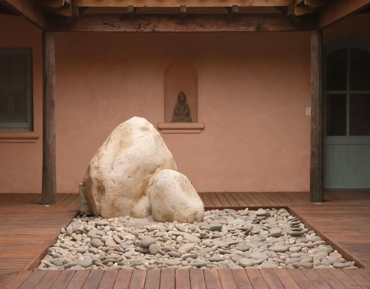 patio con rocas grandes y deck de madera — proyecto Les Confines, por Ricardo Pereyra Iraola 