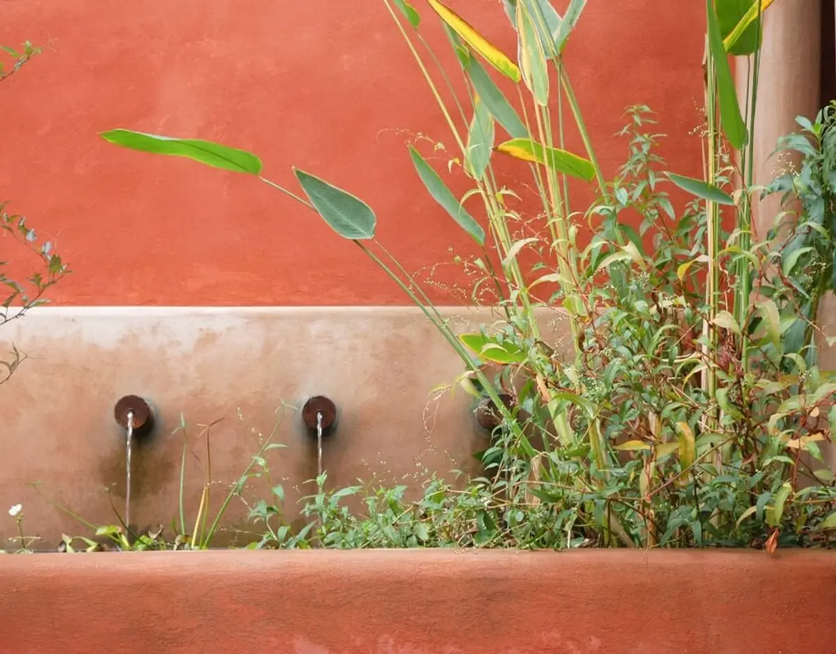 Parede terracota e vegetação exuberante com fontes — projeto Paisajismo Agua, por Ricardo Pereyra Iraola