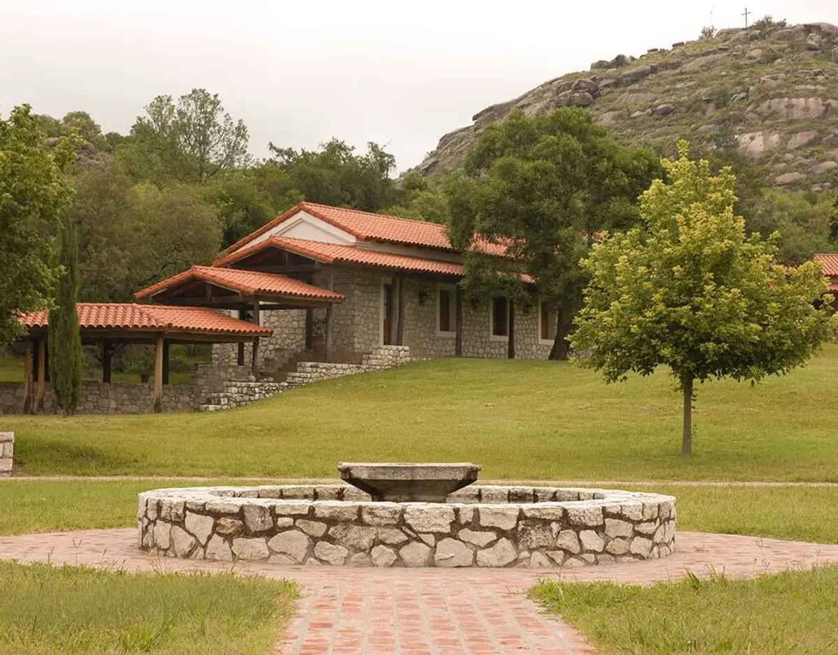 Fachada rústica com fonte em ambiente de montanha — projeto Paisajismo Agua, por Ricardo Pereyra Iraola