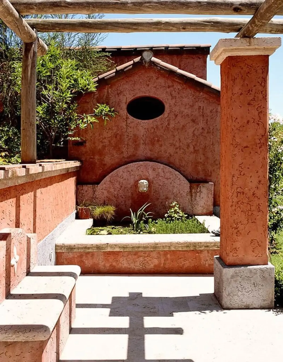 Pátio mediterrâneo com bancos de pedra e pérgola de troncos — projeto Paisajismo Agua, por Ricardo Pereyra Iraola