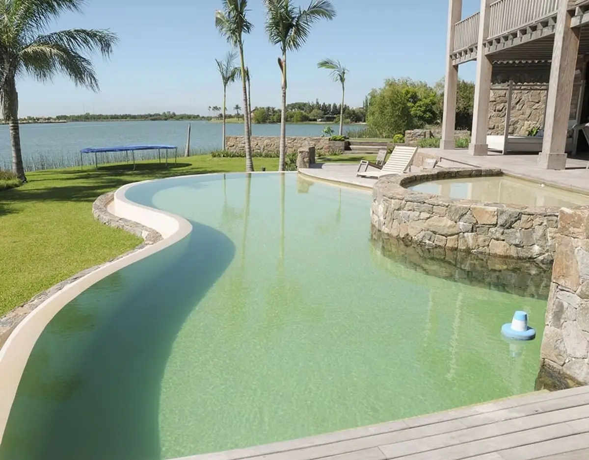 Área de piscina moderna com borda infinita e cascata de pedra — projeto Paisajismo Agua, por Ricardo Pereyra Iraola