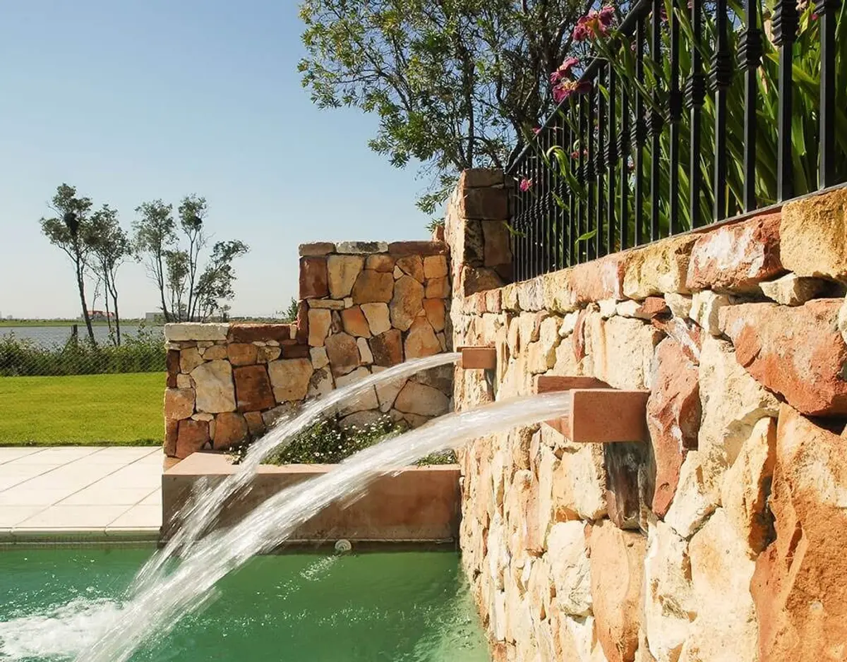Piscina exterior con pared de piedra y cascada — proyecto Paisajismo Agua, por Ricardo Pereyra Iraola 