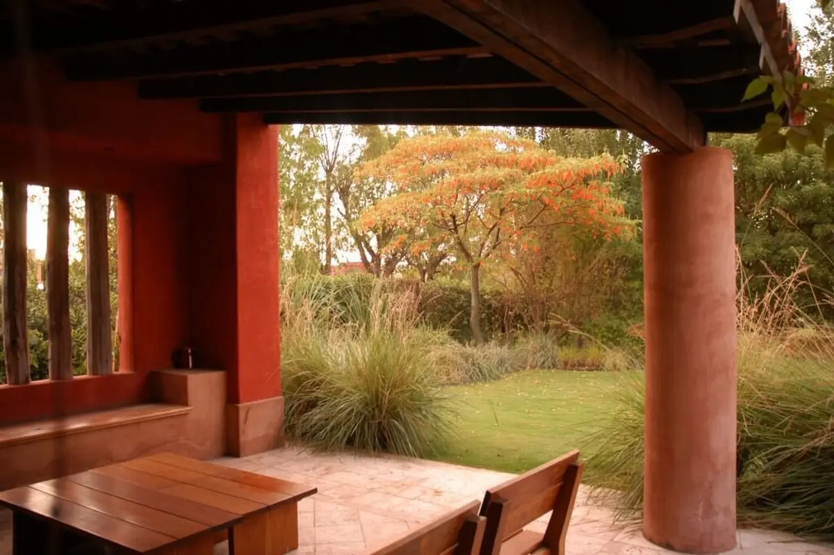 Pátio rústico mediterrâneo com pérgola de madeira e vegetação exuberante — projeto Paisajismo Aire, por Ricardo Pereyra Iraola