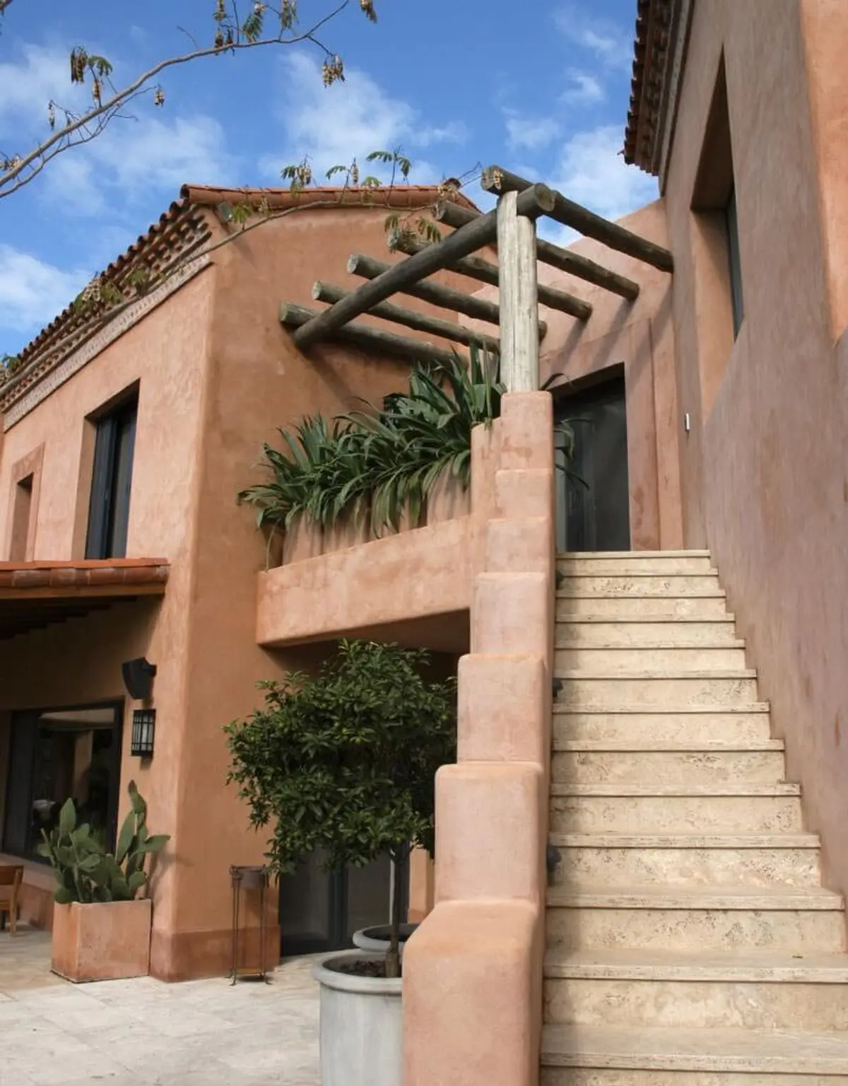 fachada mediterrânea com pérgola de madeira e escada de pedra — projeto Paisajismo Aire, por Ricardo Pereyra Iraola
