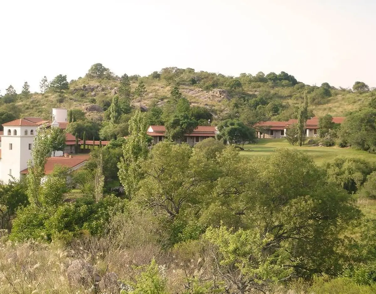 fachada de casa mediterrânea em encosta de montanha arborizada — projeto Paisajismo Aire, por Ricardo Pereyra Iraola