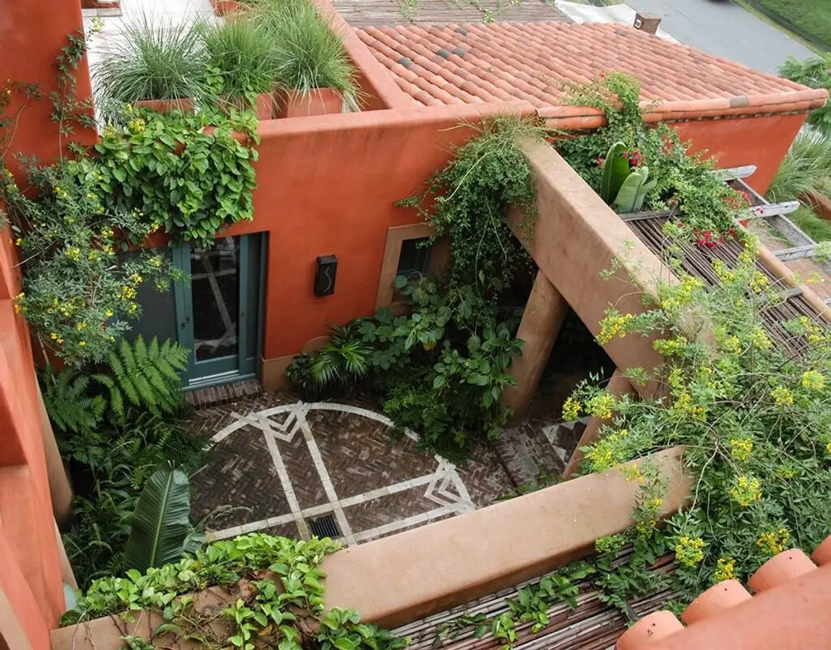 Pátio mediterrâneo exuberante com vegetação e paredes de terracota — projeto Paisajismo Tierra, por Ricardo Pereyra Iraola