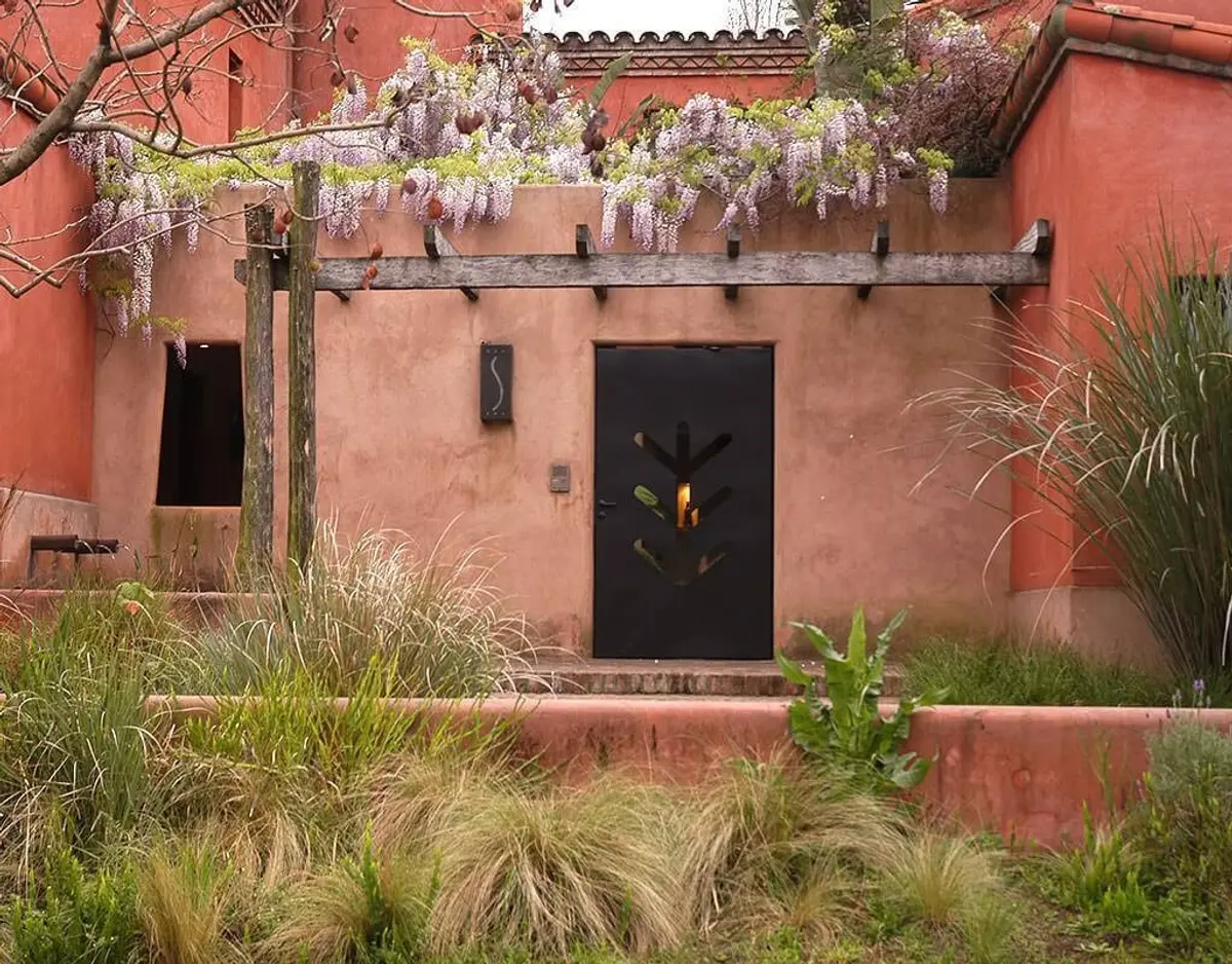 Fachada mediterrânea com porta decorativa e glicínias floridas — projeto Paisajismo Tierra, por Ricardo Pereyra Iraola