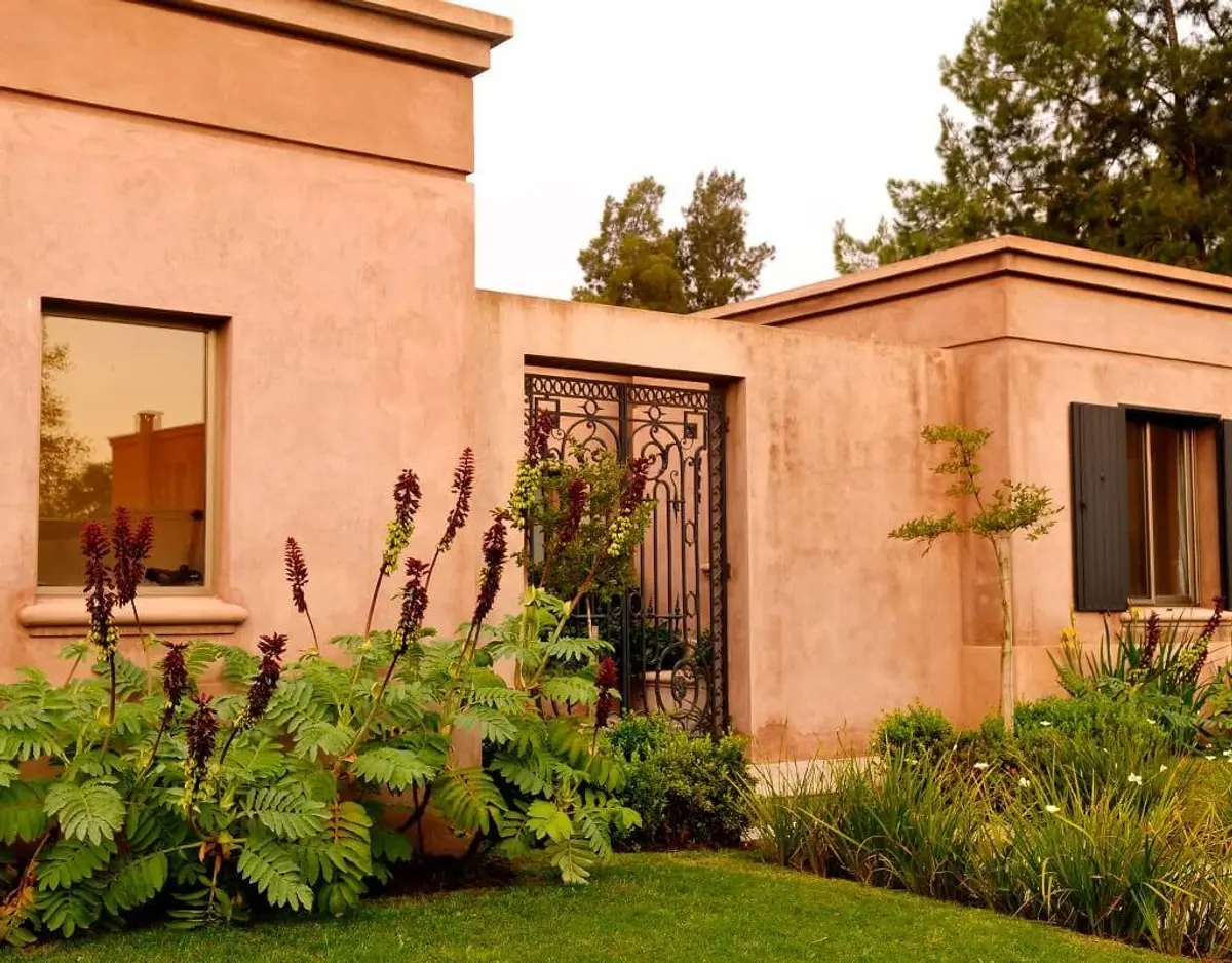 Fachada mediterrânea com estuque terracota e plantas exuberantes — projeto Patio en Flor, por Ricardo Pereyra Iraola