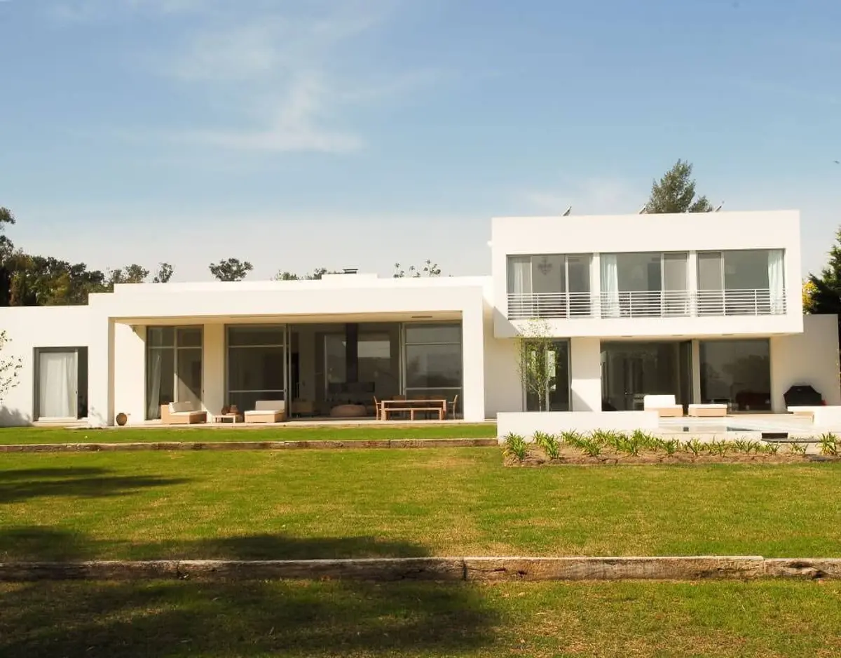 Casa moderna de concreto branco com grandes janelas e pátio — projeto Simpleza Horizontal, por Ricardo Pereyra Iraola