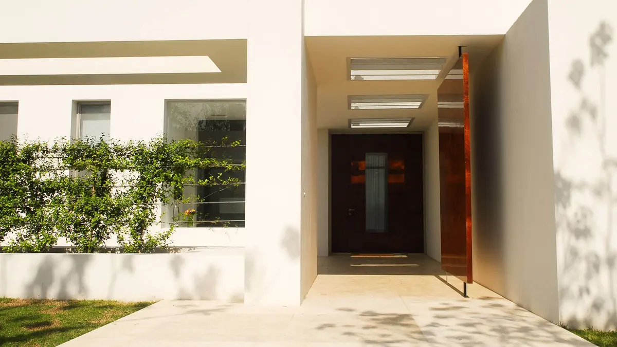 Fachada moderna com jardim vertical e porta pivotante — projeto Simpleza Horizontal, por Ricardo Pereyra Iraola