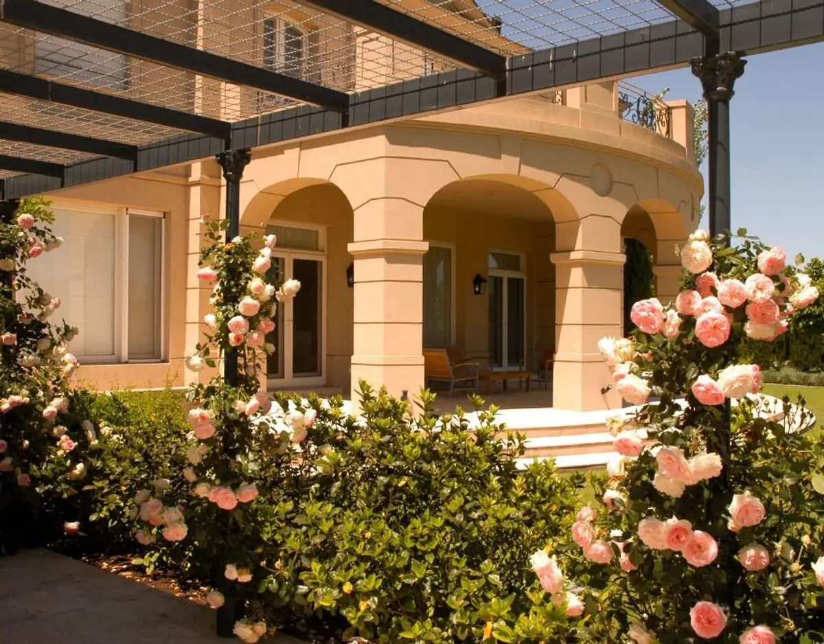 Fachada mediterránea con pérgola y vegetación exuberante — proyecto Sobriedad Clásica, por Ricardo Pereyra Iraola 