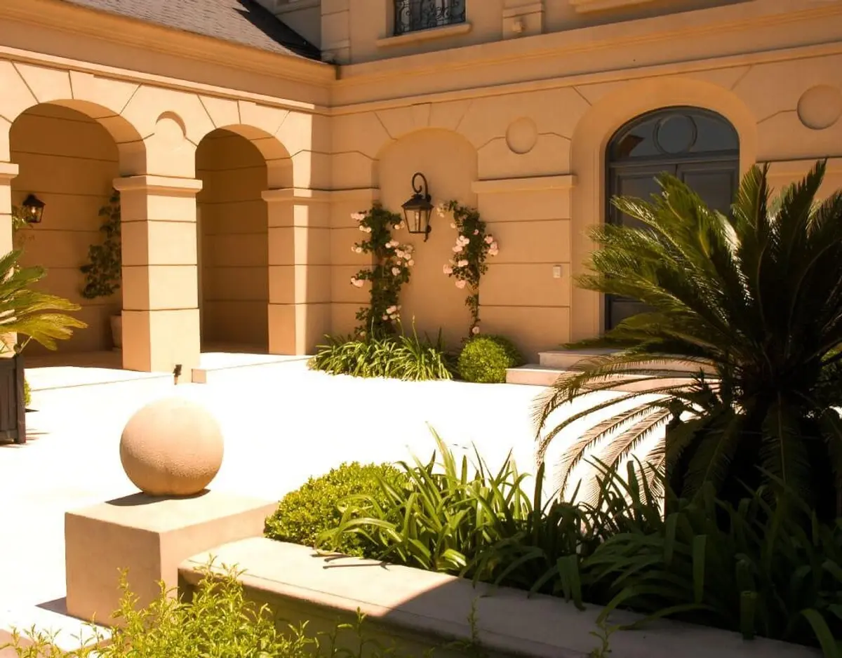 Pátio mediterrâneo com arcos, plantas e esfera decorativa — projeto Sobriedad Clásica, por Ricardo Pereyra Iraola