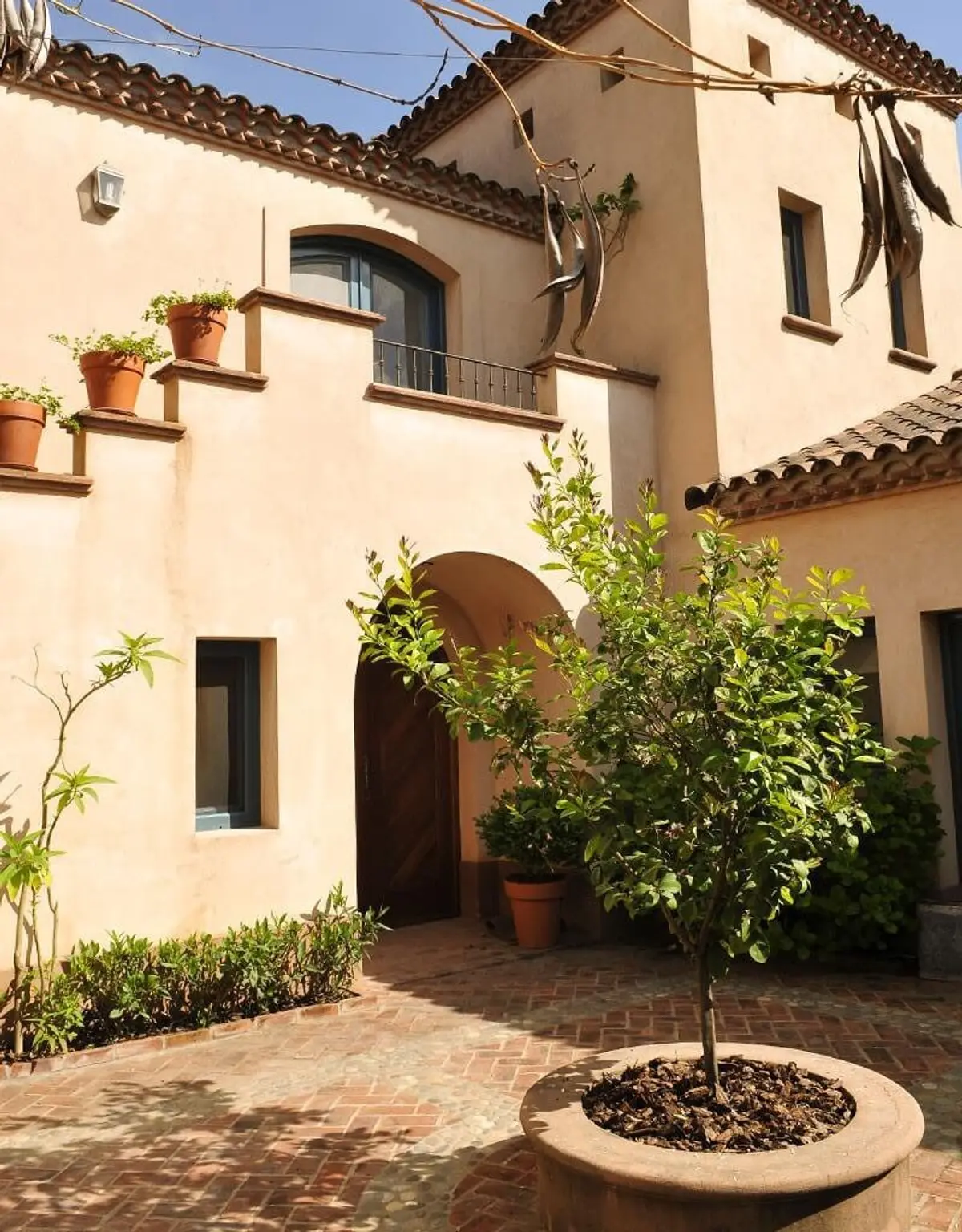 Fachada mediterránea con plantas en macetas y entrada arqueada — proyecto Un Patio Adelante, por Ricardo Pereyra Iraola 