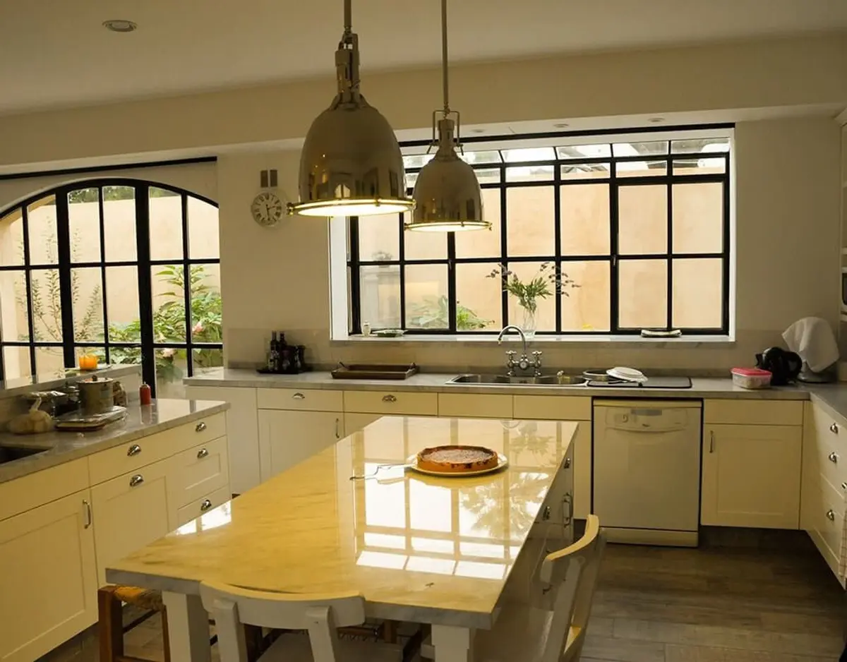 Cozinha moderna espaçosa com ilha central e janelas grandes — projeto Un Patio Interior, por Ricardo Pereyra Iraola