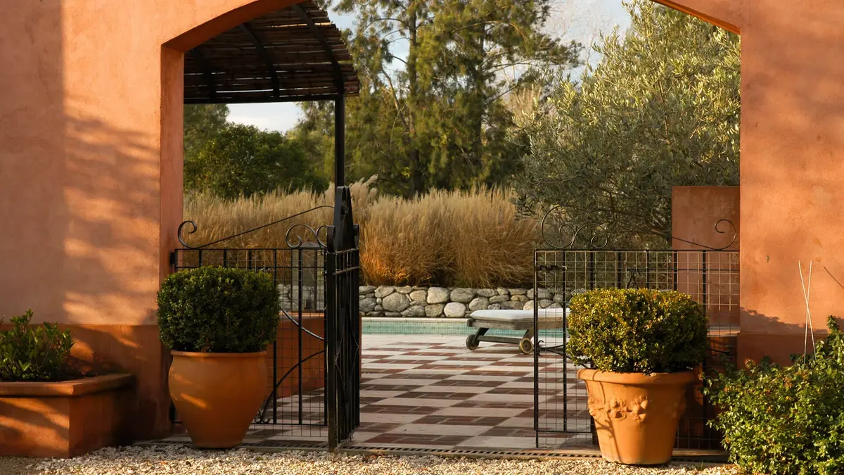 Patio mediterráneo con entrada arqueada y plantas grandes — proyecto Vivencias Salteñas, por Ricardo Pereyra Iraola 