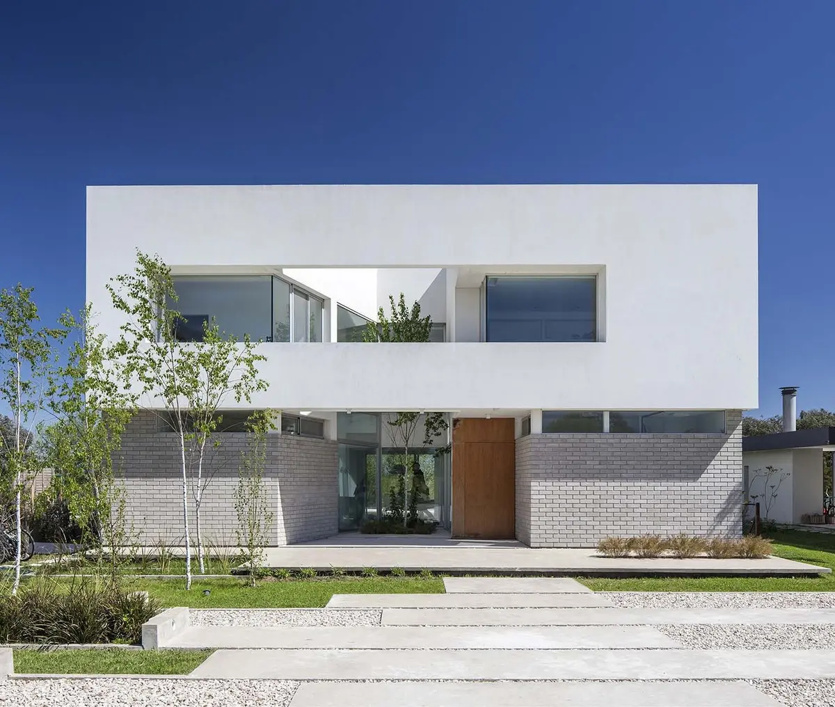 fachada moderna blanca y ladrillo gris con grandes ventanales — proyecto Casa MA, por Estudio GR, en City Bell