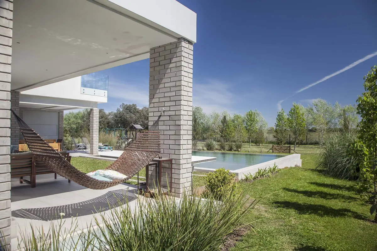 Área externa moderna com piscina, pergolado e rede — projeto Casa MA, por Estudio GR, em City Bell