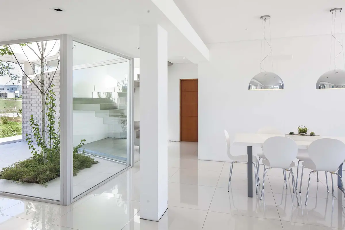 Sala de jantar moderna minimalista com luz natural e escada flutuante — projeto Casa MA, por Estudio GR, em City Bell