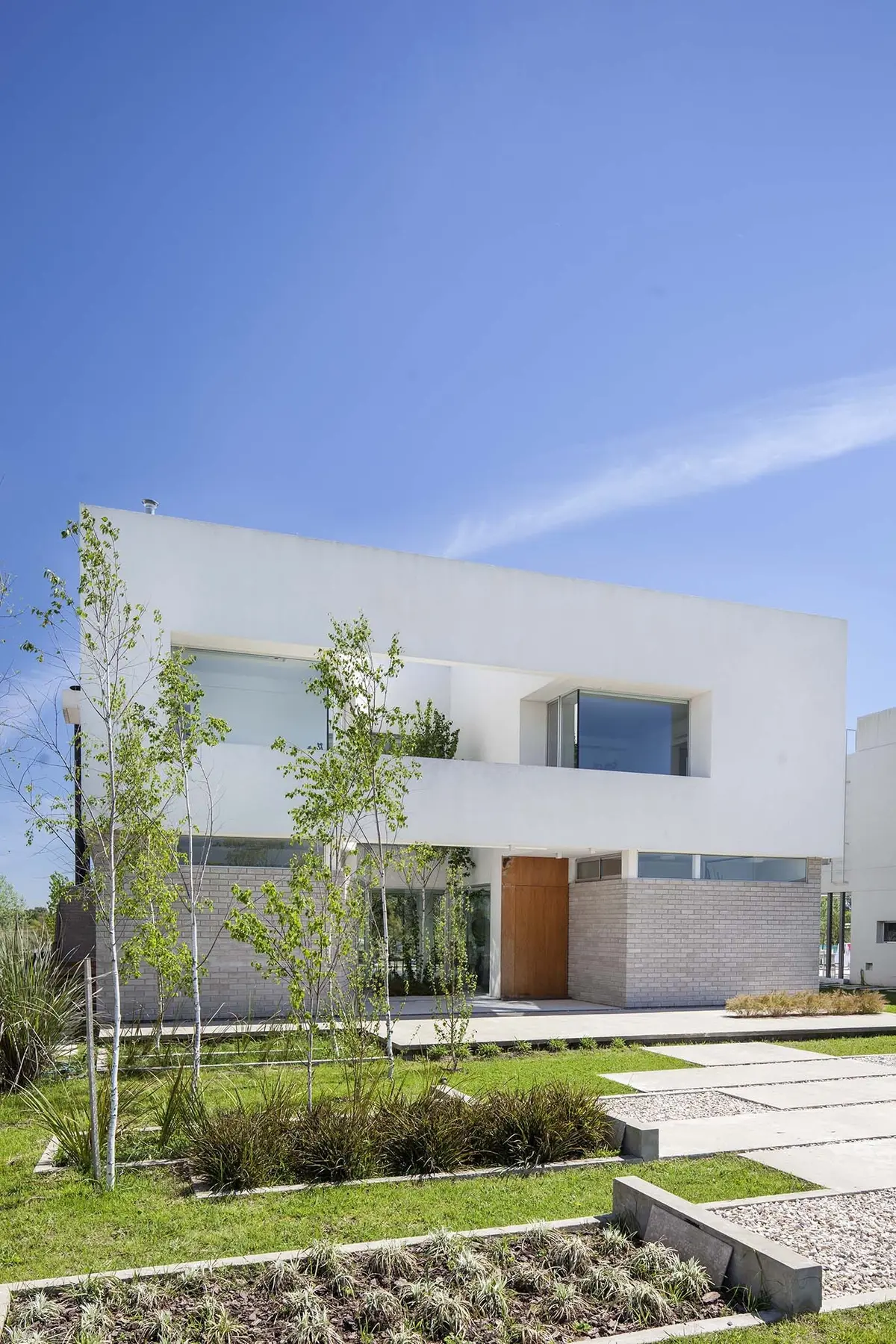 Casa moderna blanca con jardín y senderos de hormigón — proyecto Casa MA, por Estudio GR, en City Bell