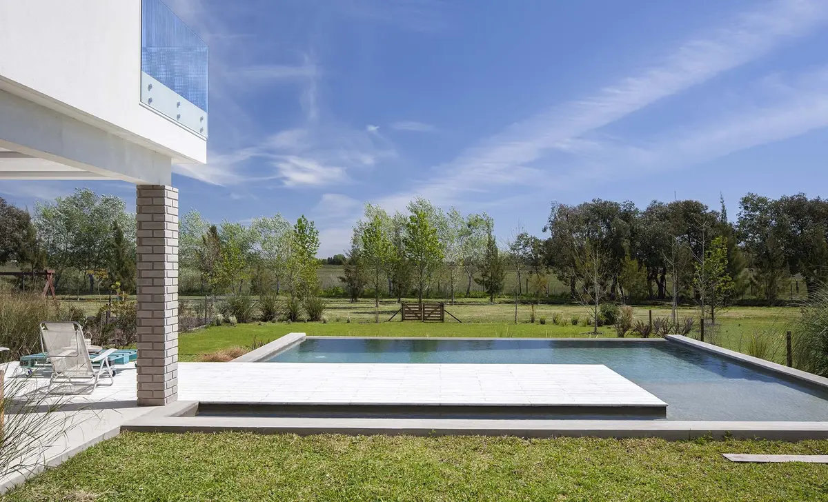 Piscina moderna com deck branco e gramado exuberante — projeto Casa MA, por Estudio GR, em City Bell