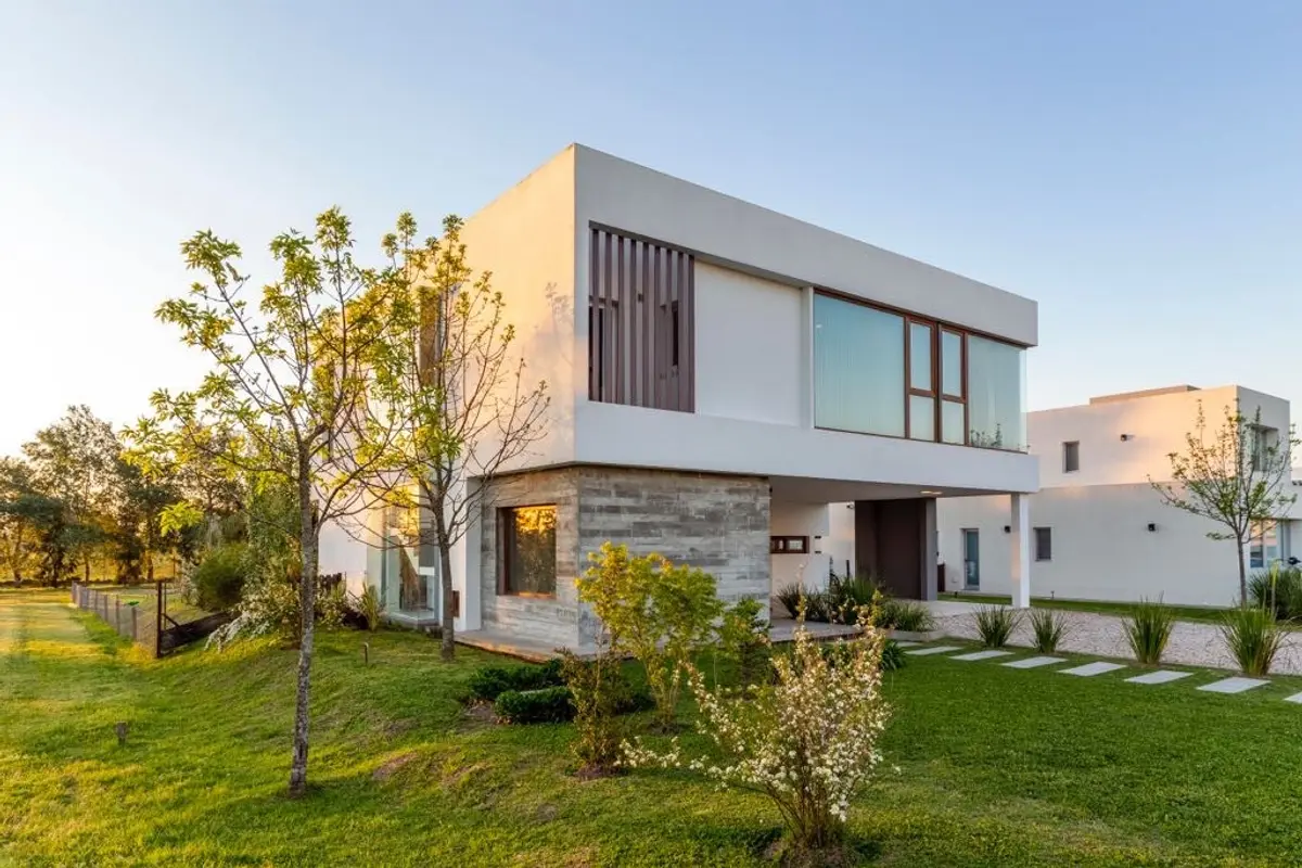 Fachada moderna con volúmenes geométricos y grandes ventanales al atardecer — proyecto Casa ME, por Estudio GR, en City Bell