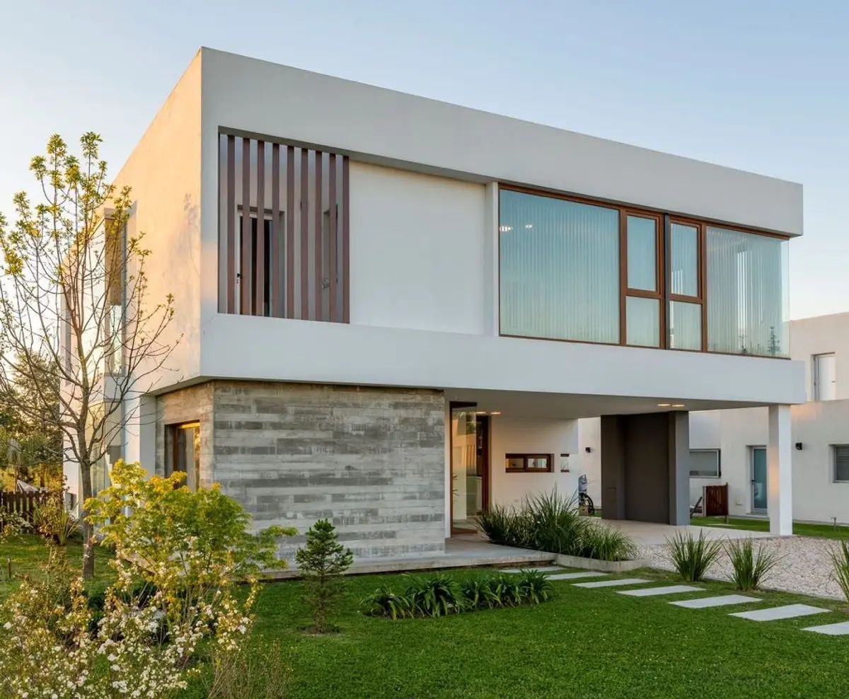 Fachada moderna con detalles en piedra y madera, amplios ventanales — proyecto Casa ME, por Estudio GR, en City Bell