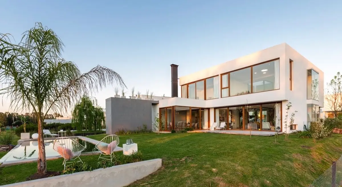 Fachada moderna con ventanales hasta el suelo y jardín exuberante — proyecto Casa ME, por Estudio GR, en City Bell