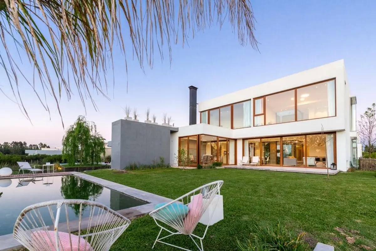Moderna casa con piscina y amplios ventanales al atardecer — proyecto Casa ME, por Estudio GR, en City Bell