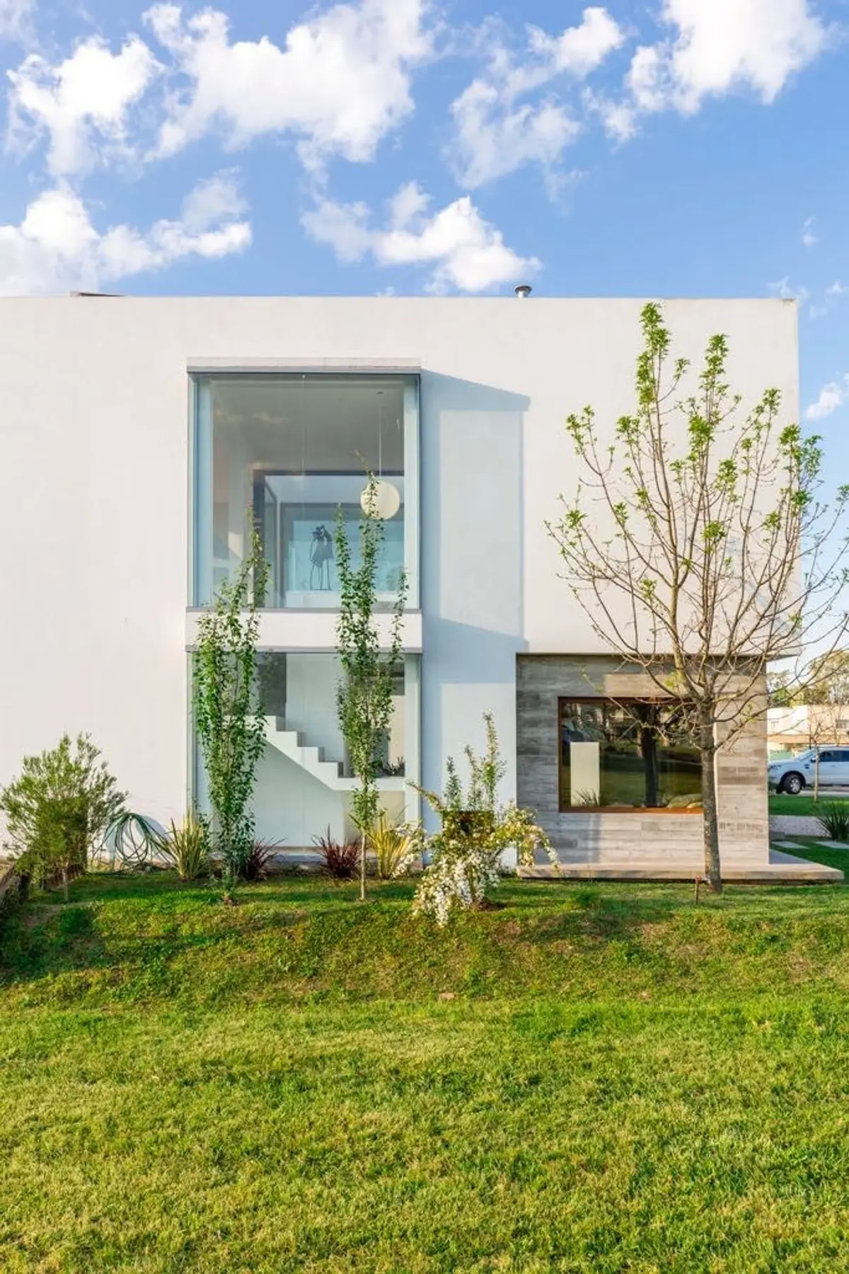 Casa moderna com amplas janelas e jardim verde — projeto Casa ME, por Estudio GR, em City Bell