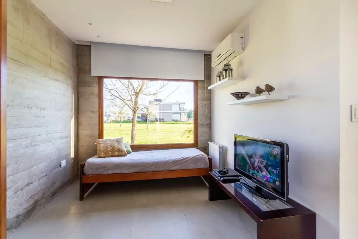 Dormitorio moderno con pared de hormigón y vista al exterior — proyecto Casa ME, por Estudio GR, en City Bell