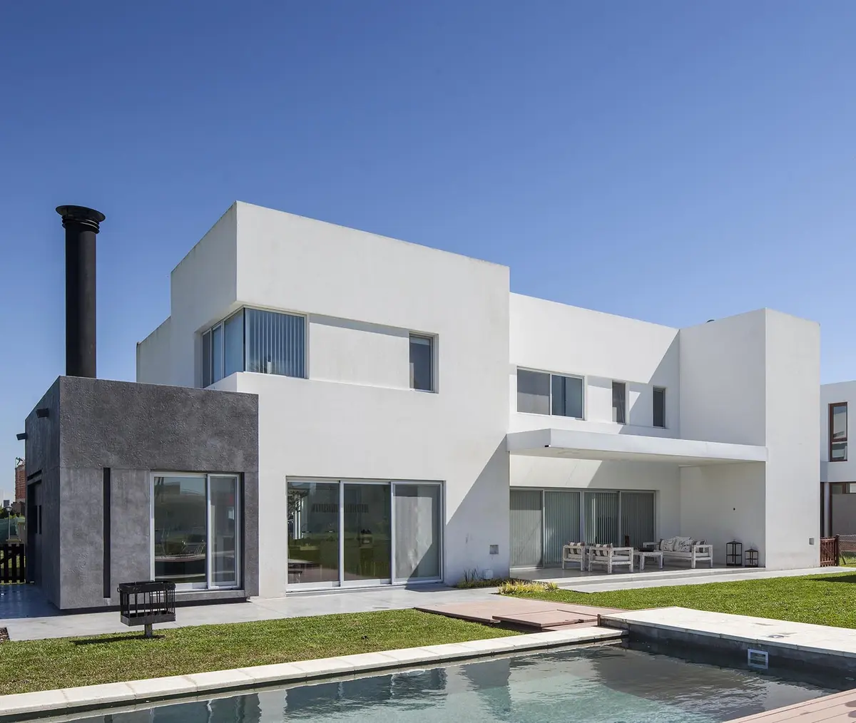 Fachada moderna com piscina e deck de madeira — projeto Casa FA, por Estudio GR, em City Bell