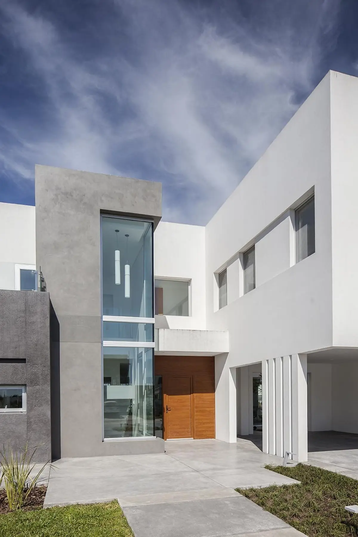 fachada moderna con entrada de cristal y hormigón — proyecto Casa FA, por Estudio GR, en City Bell