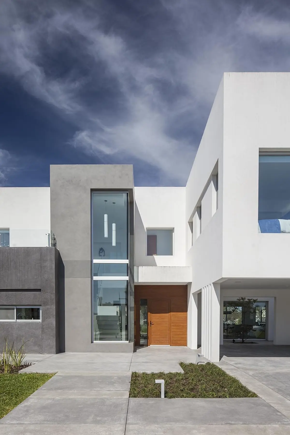Fachada moderna con volúmenes geométricos de hormigón blanco y gris — proyecto Casa FA, por Estudio GR, en City Bell