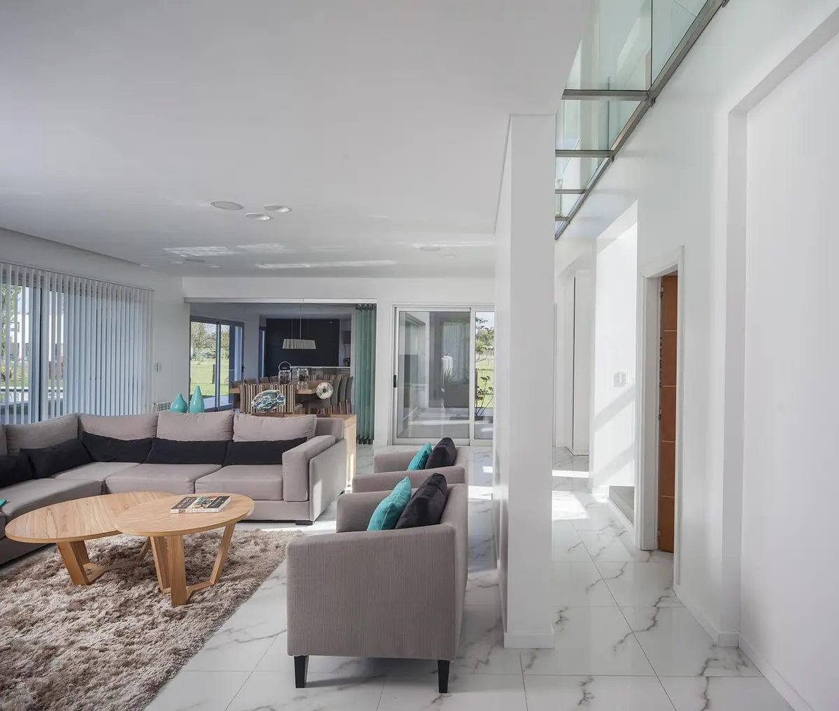 Living moderno minimalista con grandes ventanales y suelo de mármol — proyecto Casa FA, por Estudio GR, en City Bell