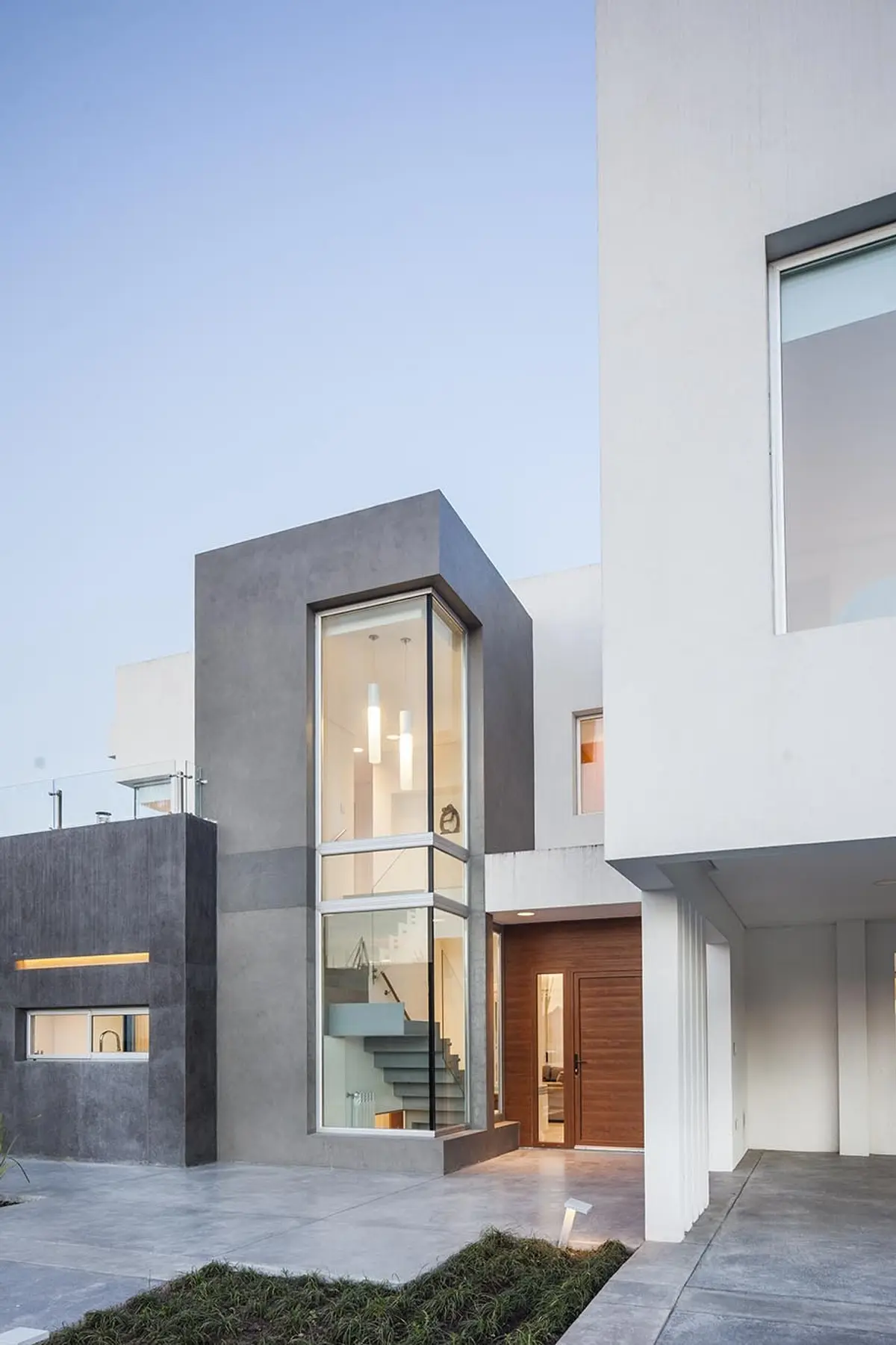 fachada moderna de hormigón con escalera de vidrio y madera — proyecto Casa FA, por Estudio GR, en City Bell