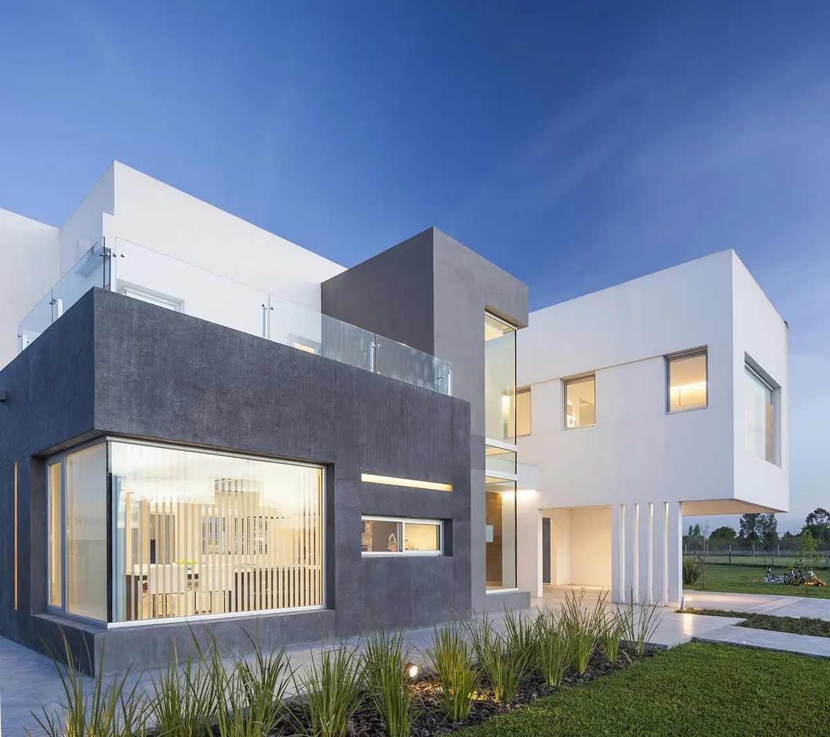 Fachada moderna con volúmenes geométricos y grandes ventanales — proyecto Casa FA, por Estudio GR, en City Bell