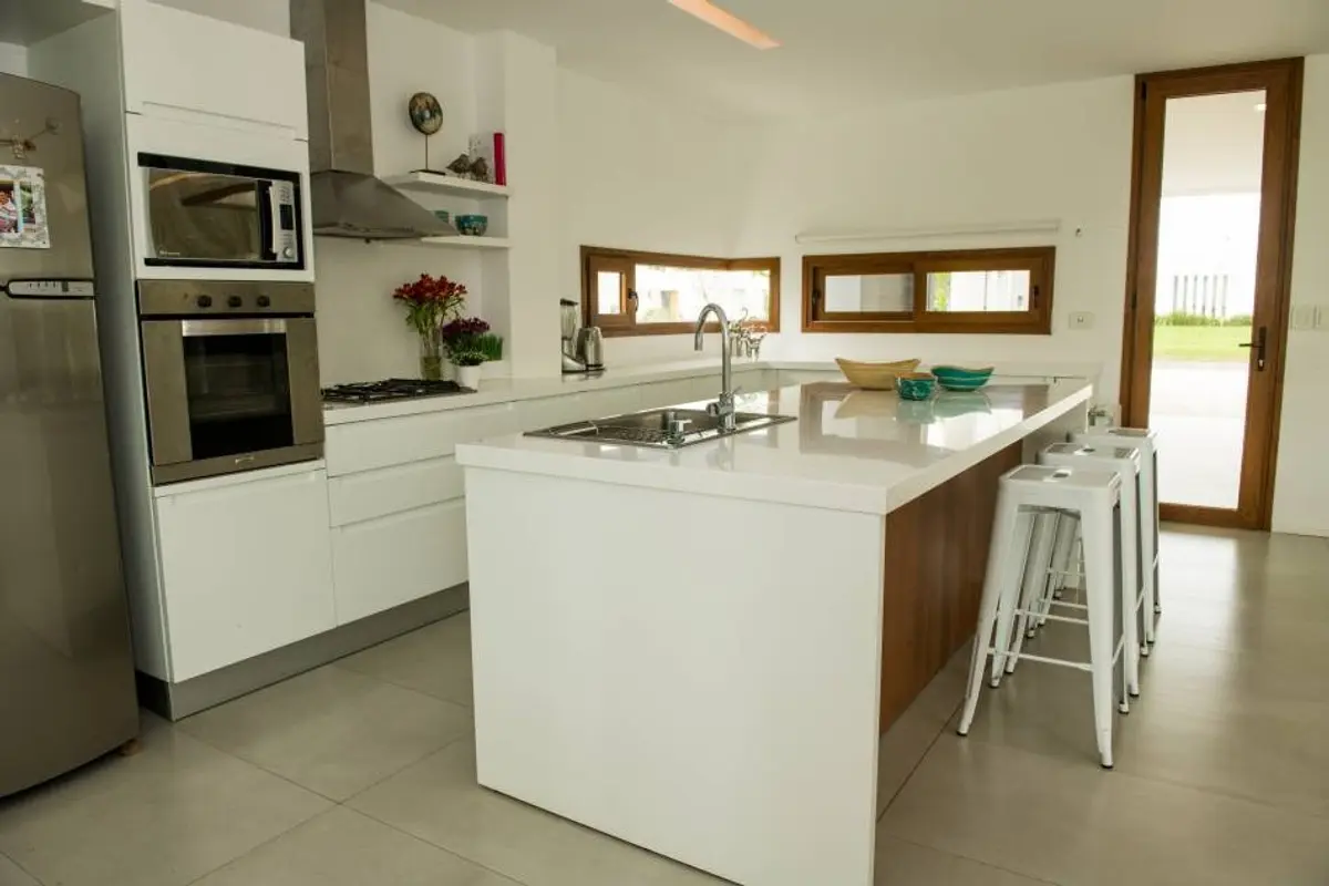 Cozinha moderna com ilha, branca e inox — projeto Casa ME, por Estudio GR, em City Bell
