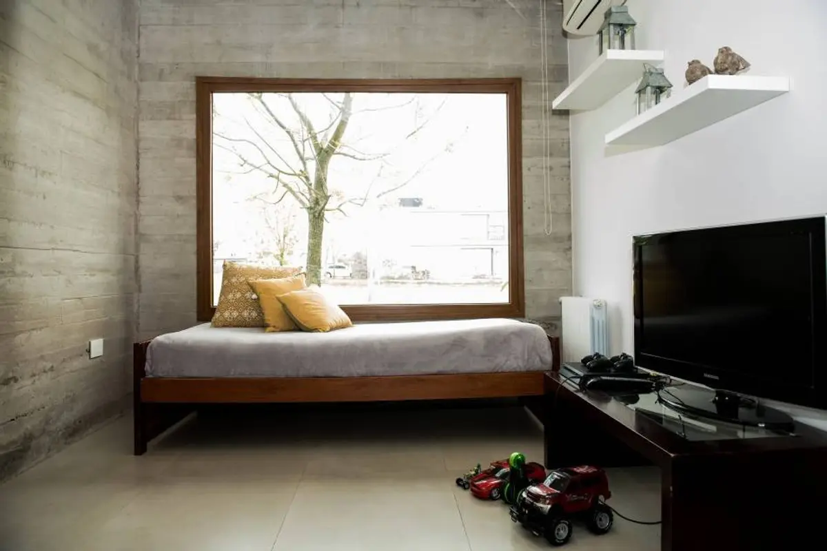 Dormitorio moderno con paredes de cemento y gran ventanal — proyecto Casa ME, por Estudio GR, en City Bell